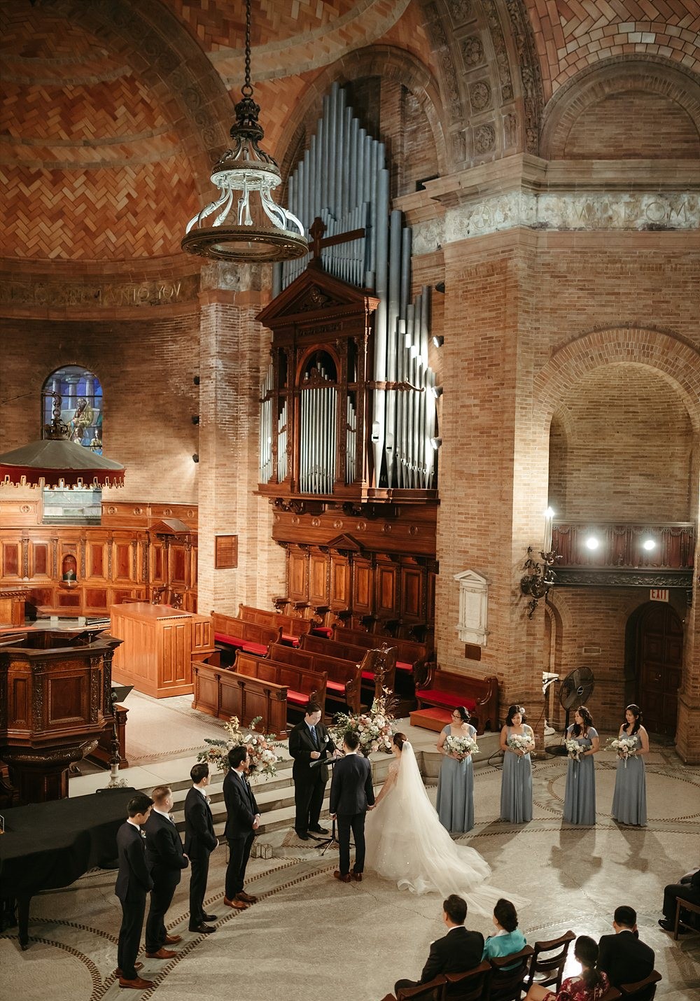 A couple flanked by their wedding party getting married in St. Paul's Chapel