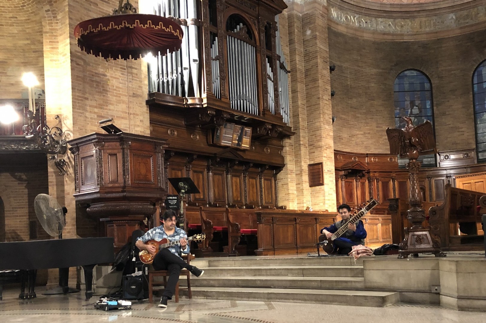 Two musicians playing Indian instruments in St. Paul's Chapel. 