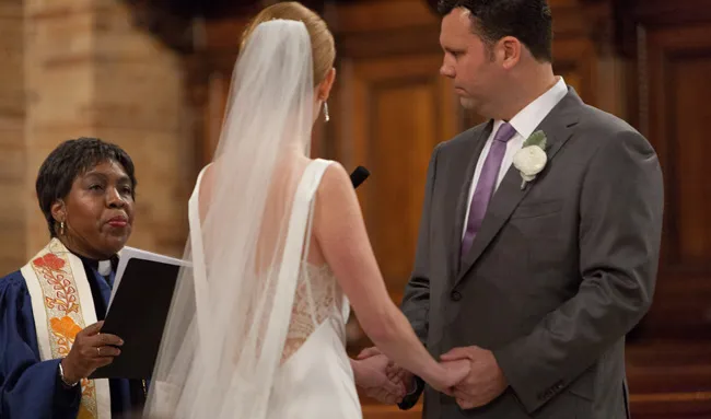 Chaplain Davis officiating a wedding in the Nave of St. Paul's Chapel for a bride and groom.